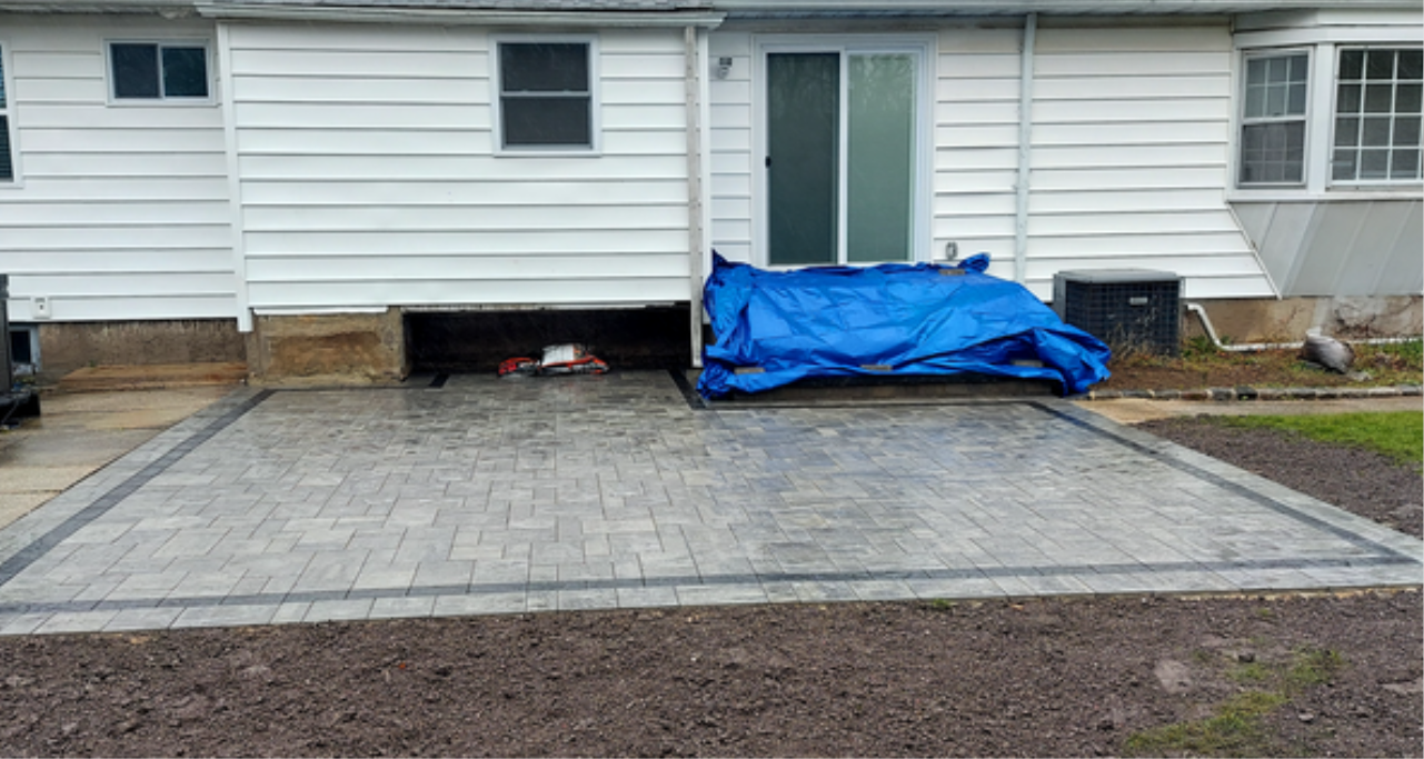 Sweeping polymeric sand into the gaps between finished stones, completing the final phase of how to install patio pavers correctly.
