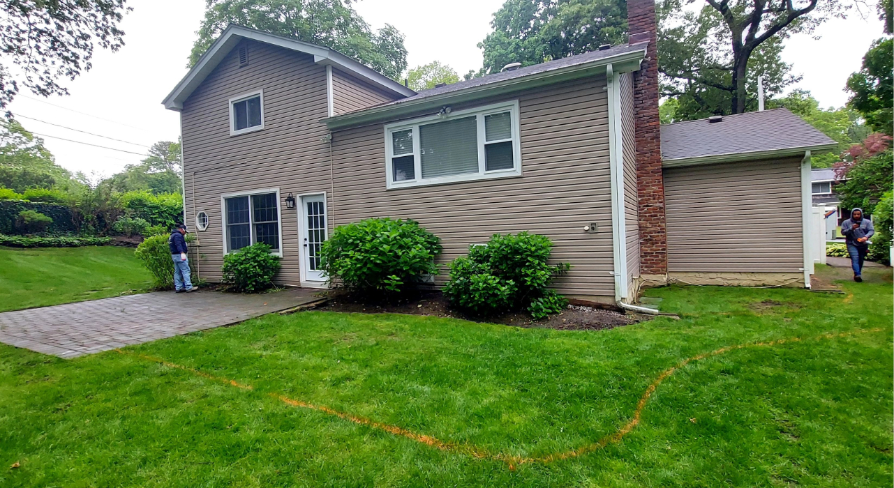 A residential backyard during the excavation phase, cleared and leveled in preparation for a stable patio paver base.