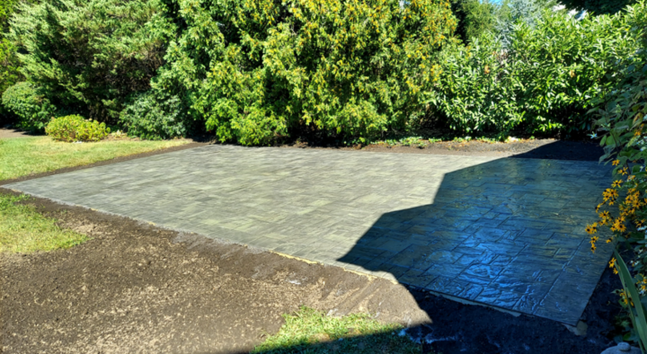 Sleek grey paving stones surrounded by lush landscaping, an excellent example of modern and refreshing small patio design ideas.