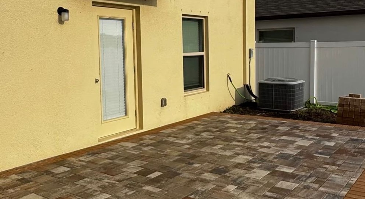 A unique circular paver section beside a white fence offers incredibly creative waterfront backyard patio design ideas for homeowners today.