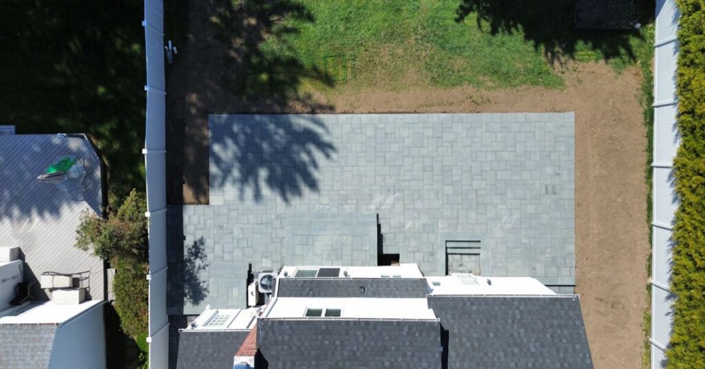 custom paver patio installation ideas for a Suffolk County backyard with dining, grill, and seating zones