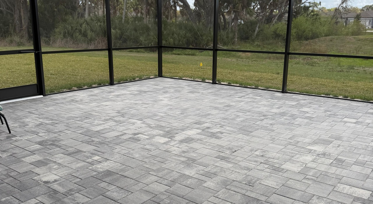 An exterior view of a beige home showcases comfortable patio furniture safely resting inside high quality custom lanai screen enclosures.