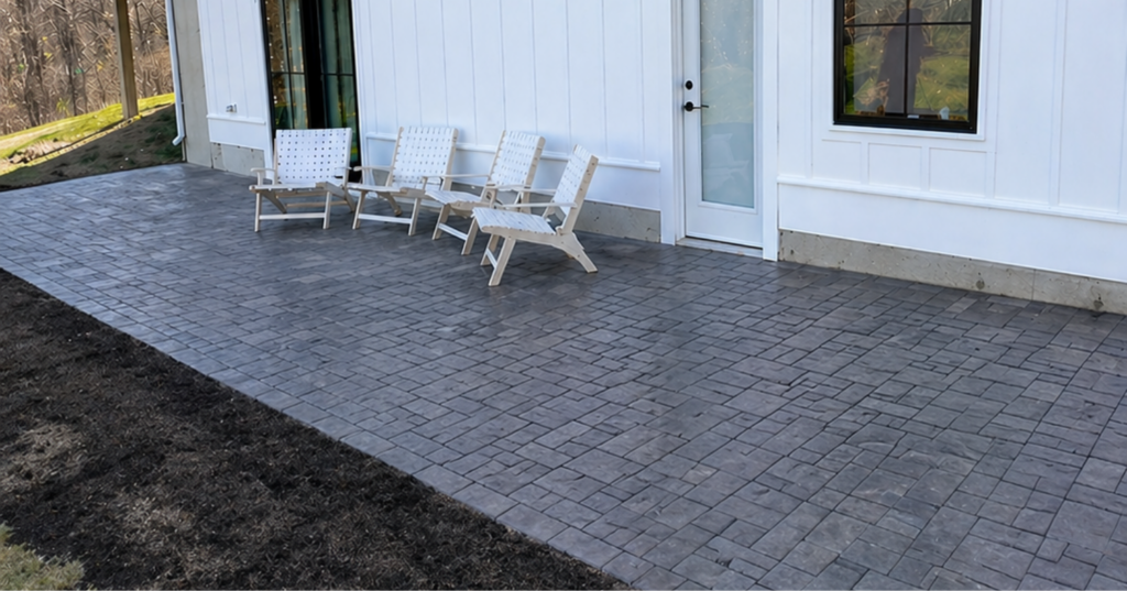 White outdoor chairs sit on a beautifully finished grey patio installed perfectly by a paver patio contractor in Manchester today.