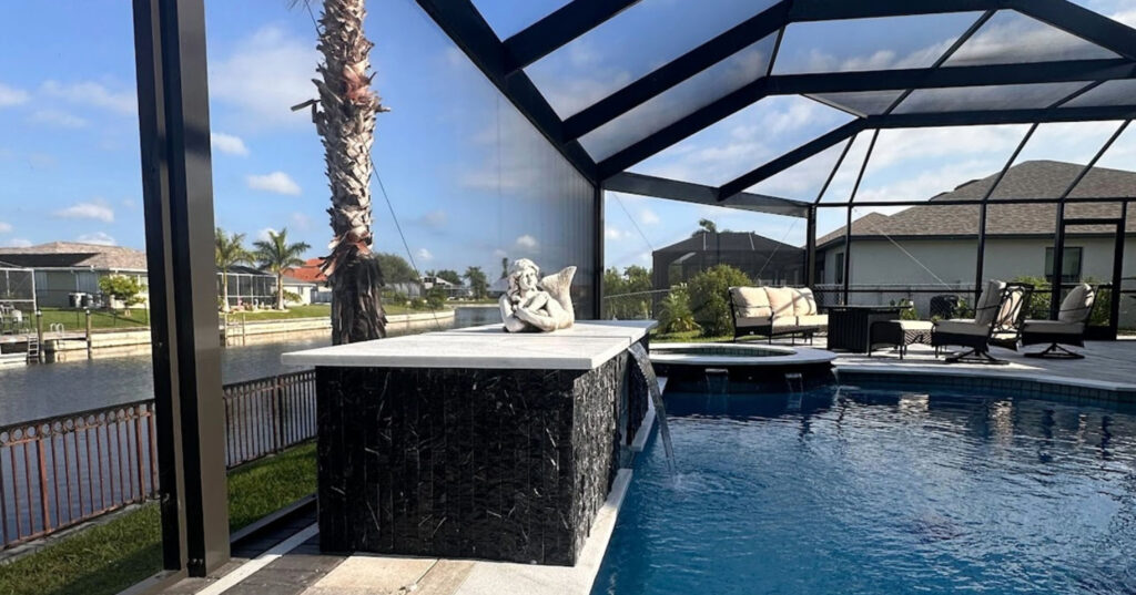 A beautiful backyard swimming pool featuring a unique stone statue highlights the luxurious appeal of modern pool screen enclosures perfectly.