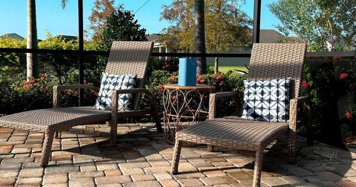 Two outdoor lounge chairs set on a paver patio highlighting budget friendly lanai enclosure options.