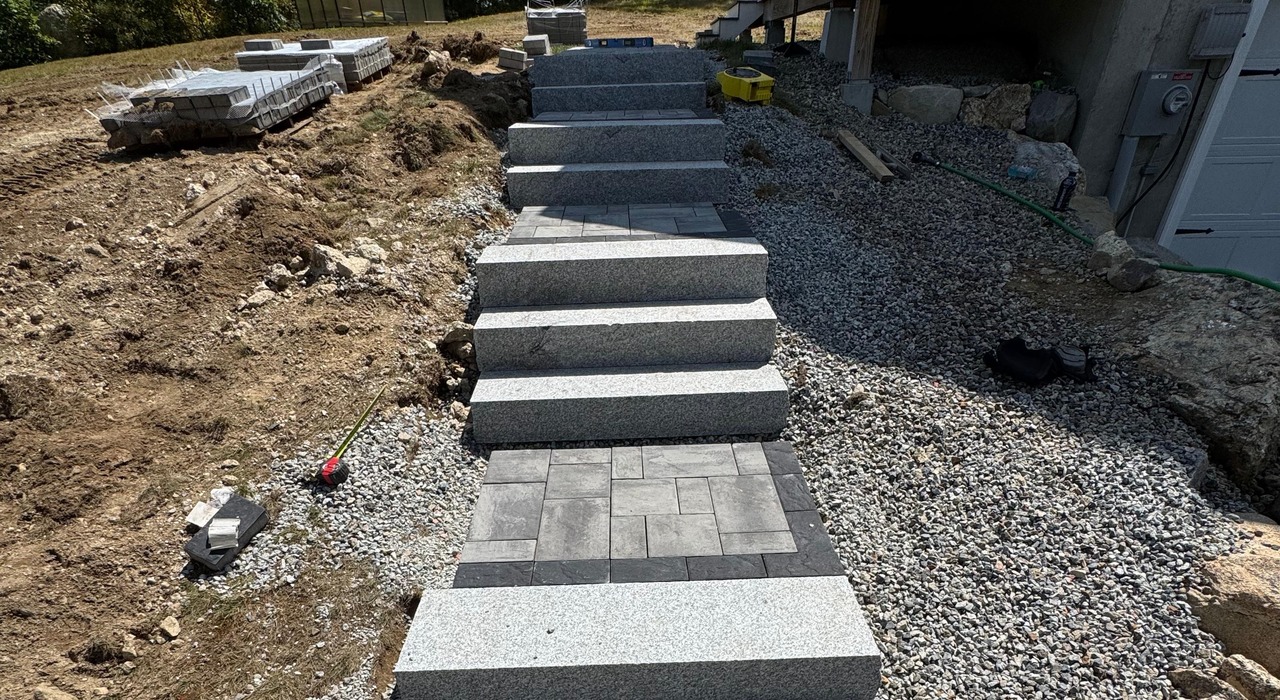 A backyard construction site showing a step-by-step granite steps installation in Nashua