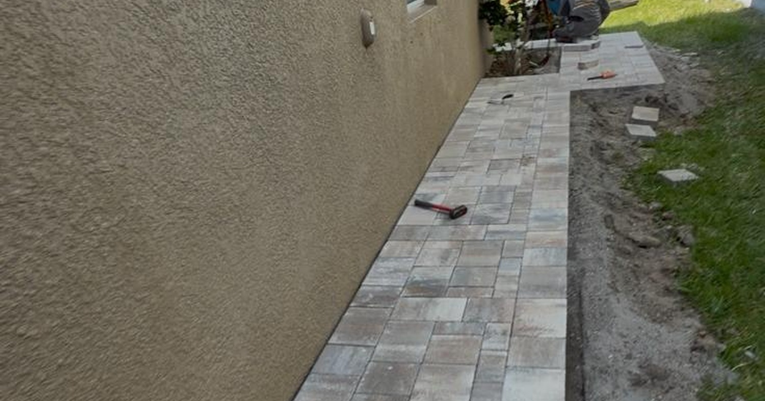 Finished stone path by a wall showing how to install a walkway with pavers.