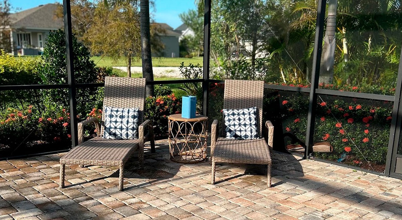 Wicker lounge chairs inside a screened patio showing how much does a lanai cost in Florida