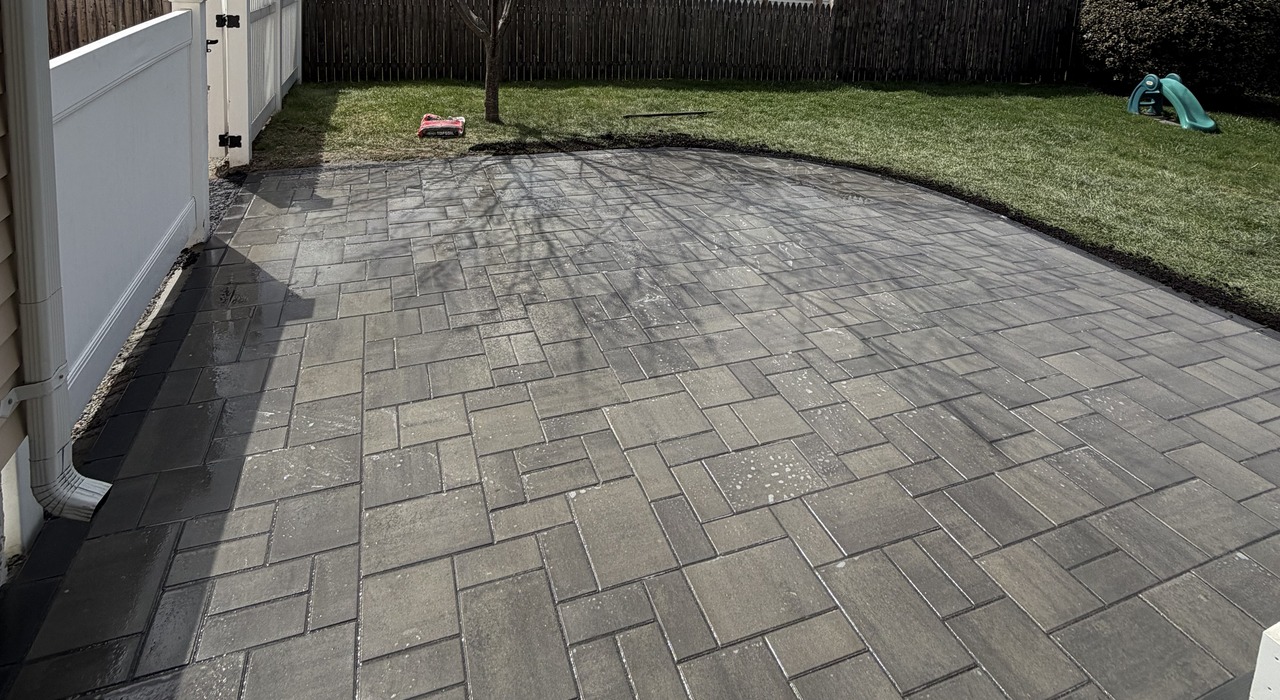 A spacious curved backyard stone patio designed by expert patio contractors in Nashua.