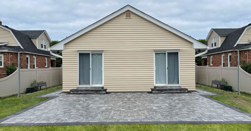 A wide grey paver patio installation designed to prevent issues with why paver patios sink