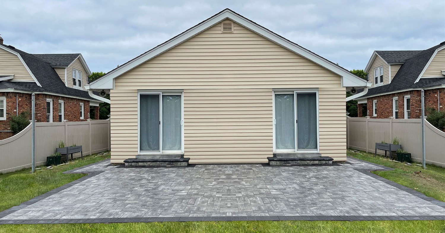 A wide grey paver patio installation designed to prevent issues with why paver patios sink