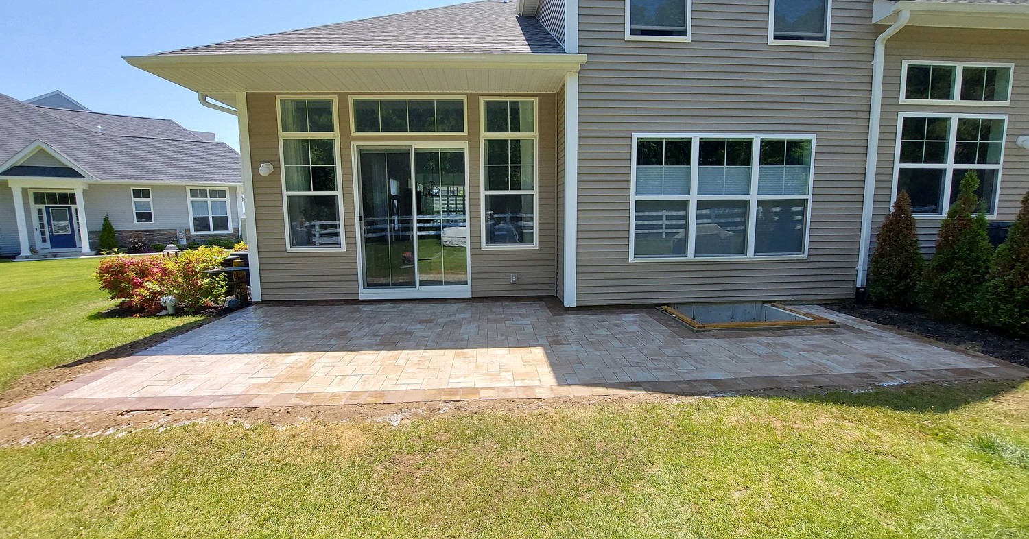 Freshly laid grey pavers outside a home during spring patio preparation.